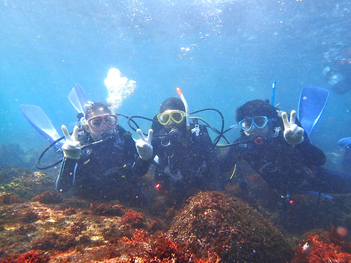 水中で3人そろってピースサインをする体験ダイビング参加者